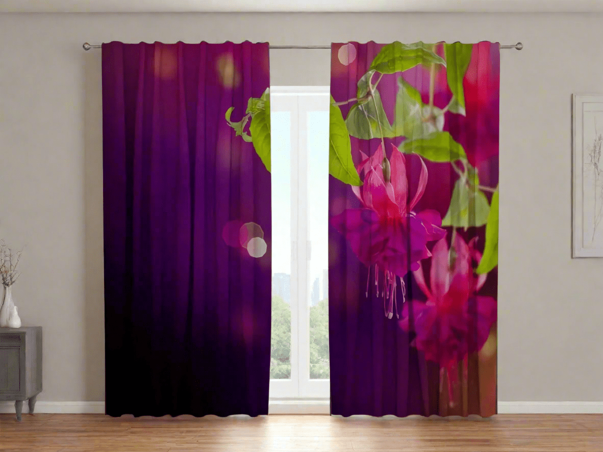 Interior of a bright room with a wooden floor. Photo curtains with an asymmetrical design in deep purple and lilac tones are hung on the window. The right curtain panel features a photorealistic depiction of large, bright fuchsia flowers with green leaves, while the left panel is dominated by a dark purple background with blurred circles of light, or a bokeh effect. A window is visible in the center.