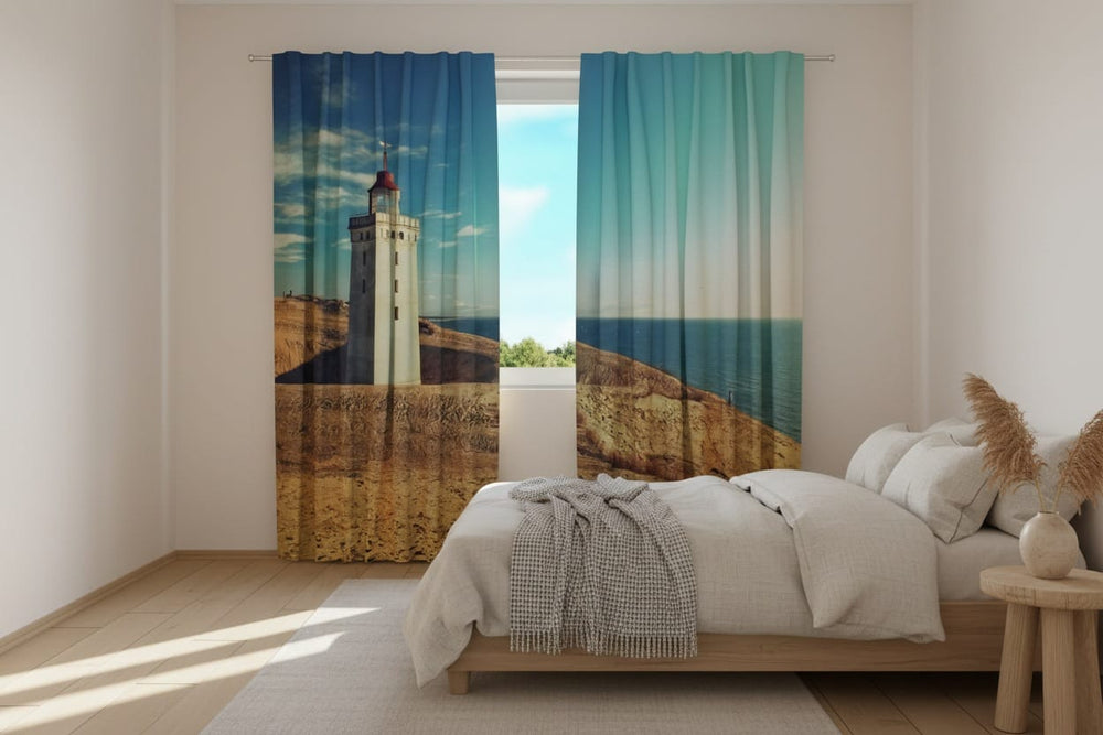 Gaišas guļamistabas interjers ar baltām sienām un koka grīdu. Uz loga uzstādīti fotoaizkari, uz kuriem fotoreālistiski attēlota smilšaina piekrastes ainava. Uz kreisā aizkaru paneļa redzama balta, vēsturiska bāka, kas stāv stāvā smilšu kāpā pret tumši zilām debesīm. Uz labā paneļa kāpas nogāze turpinās, atklājot skatu uz plašu, mierīgu zilu jūru. 