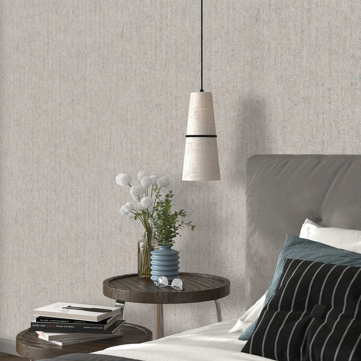 Light gray relief-textured wallpaper in a bedroom interior with a wooden nightstand, books, a blue decorative vase, and white flowers