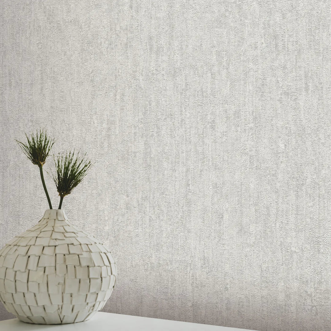 Light gray plaster-textured wallpaper in a modern interior with a white mosaic vase and green plants