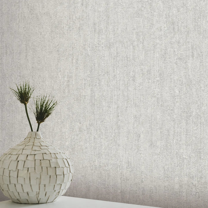 Light gray plaster-textured wallpaper in a modern interior with a white mosaic vase and green plants