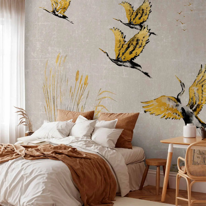 Photo wallpaper with golden cranes and a nature motif in a bedroom interior behind a double bed with white and warm brown bedding and a wooden plank floor