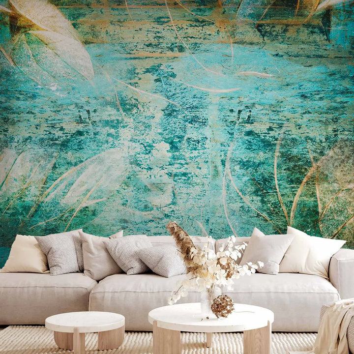 Abstraktne fototapeet vana, kriimustatud tekstuuriga sügavates türkiisi, sinistes ja rohelistes toonides, mida täiendavad suuremõõtmelised, osaliselt läbipaistvad kuldsed ja pruunid puulehtede siluetid.
